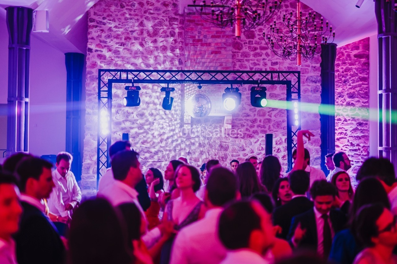 Groupe de personnes dansant dans une salle éclairée par des lumières colorées et des projecteurs.