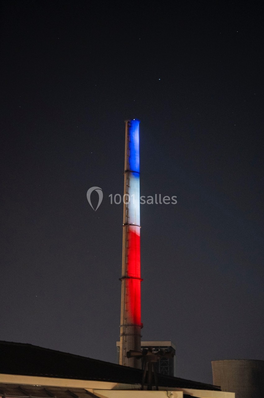 Cheminée illuminée aux couleurs bleu, blanc et rouge dans un paysage nocturne.