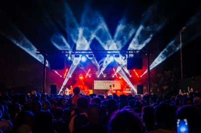 Plateforme circulaire avec un anneau lumineux sur pied, installée sur une pelouse devant un mur en pierre couvert de lierre.