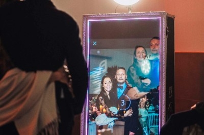 Un groupe de personnes pose devant un miroir interactif éclairé par une lumière circulaire dans un cadre festif.