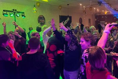 Scène décorée avec guirlandes lumineuses, plantes et une table de DJ éclairée en bleu et blanc.