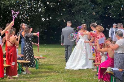 Scène décorée avec guirlandes lumineuses, plantes et une table de DJ éclairée en bleu et blanc.