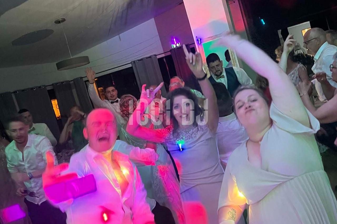 Des personnes dansent et s'amusent lors d'une fête en intérieur, avec des lumières colorées en arrière-plan.