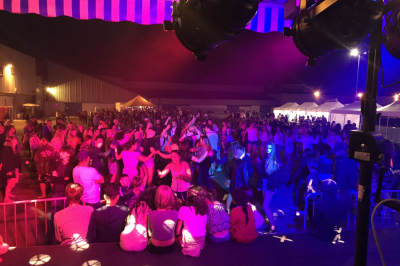 Stand de DJ avec éclairage LED rouge et vert, installé dans une salle avec décoration intérieure et lumière naturelle.