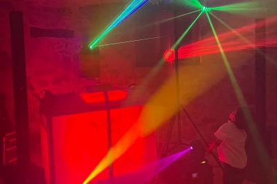 Stand de DJ avec éclairage LED rouge et vert, installé dans une salle avec décoration intérieure et lumière naturelle.