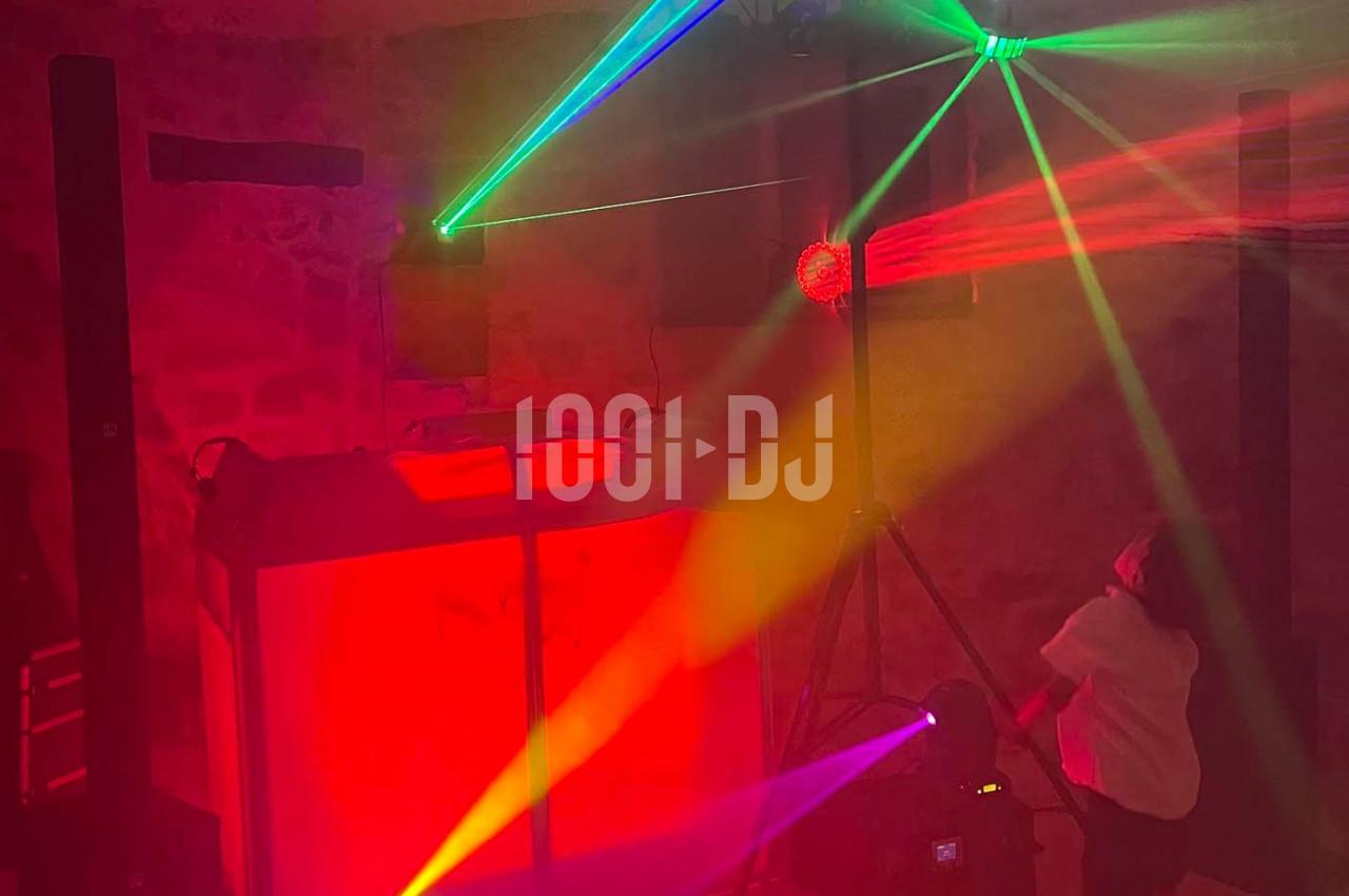 Jeu de lumières colorées avec lasers et projecteurs éclairant une salle sombre équipée d'un stand de DJ.