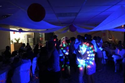 Des personnes dansent dans une salle faiblement éclairée, illuminée par des lumières colorées.