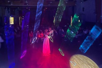 Un couple danse au centre d'une salle sombre éclairée par des lumières colorées et des projecteurs.