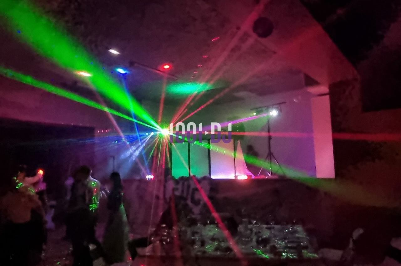 Salle sombre avec des jeux de lumières colorées et des personnes dansant sous des faisceaux laser.