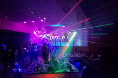 Salle sombre avec des jeux de lumières colorées et des personnes dansant sous des faisceaux laser.