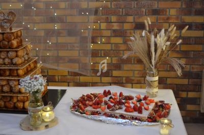 Table décorée avec une pièce montée, un plateau de fraises, des bougies et un bouquet de fleurs séchées devant un mur en…