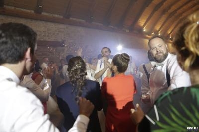 Un groupe de personnes danse et s'amuse dans une salle en pierre avec un éclairage chaleureux.