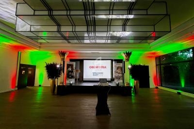 Salle de réception décorée de lumières vertes et rouges, avec une scène et un écran de projection au fond.