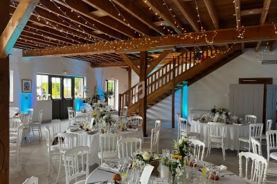 Salle de réception décorée avec des tables rondes dressées, des guirlandes lumineuses et une ambiance chaleureuse.