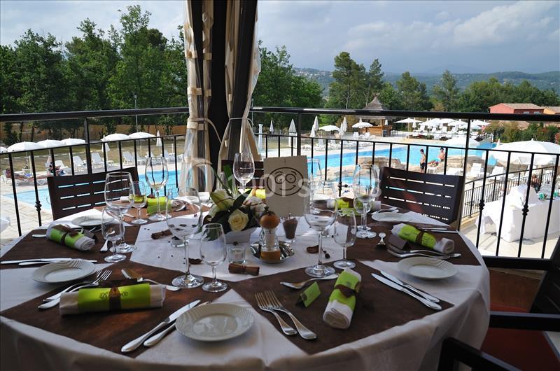 Table dressée avec élégance sur une terrasse, offrant une vue sur une piscine et un paysage verdoyant en arrière-plan.