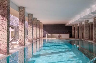 Chambre lumineuse avec un lit double, une table de chevet, une lampe et une salle de bain attenante visible en arrière-plan.