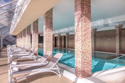 Chambre lumineuse avec un lit double, une table de chevet, une lampe et une salle de bain attenante visible en arrière-plan.