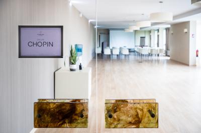 Chambre lumineuse avec un lit double, une table de chevet, une lampe et une salle de bain attenante visible en arrière-plan.