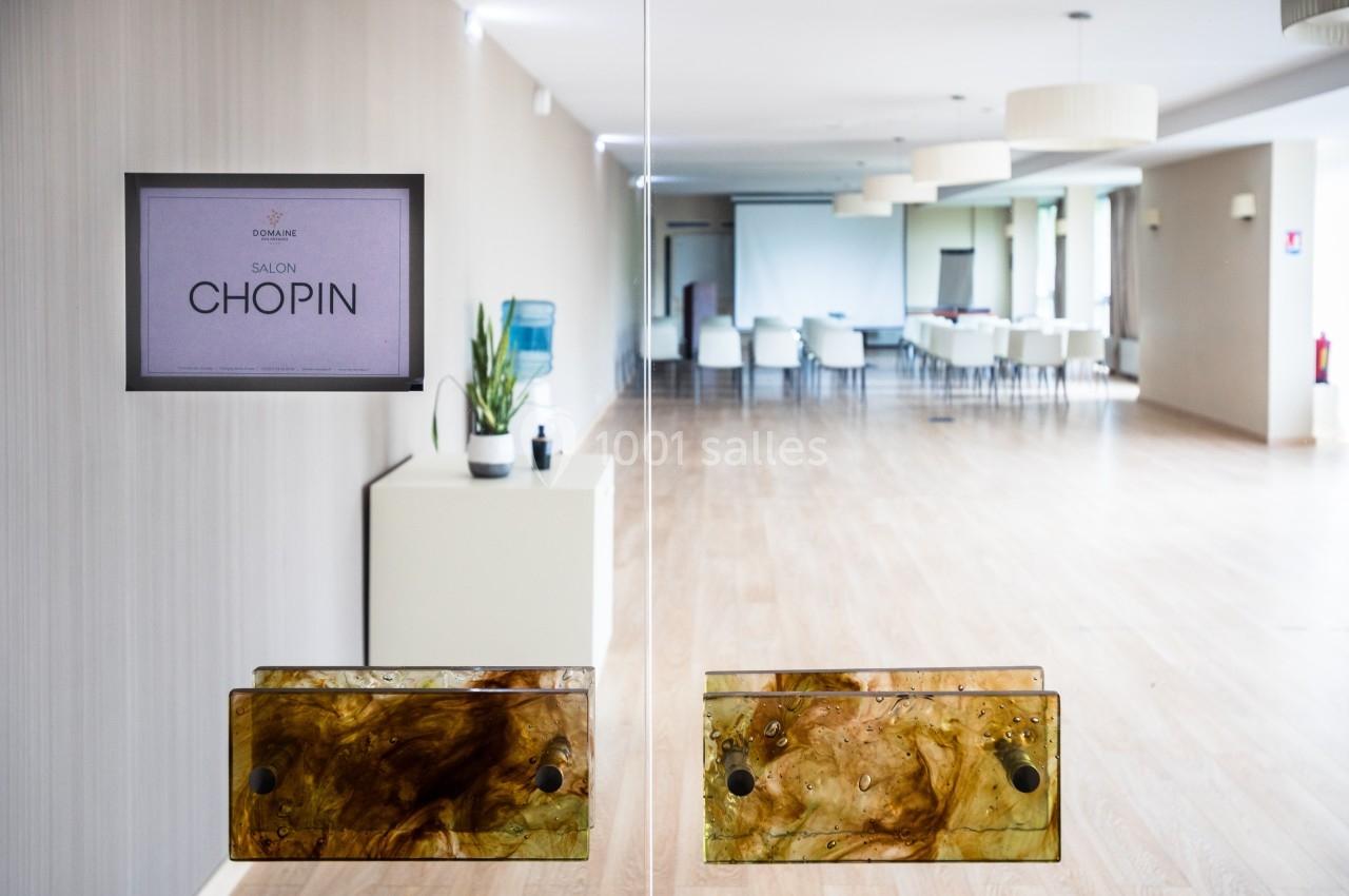 Vue d'une salle de réunion lumineuse avec des chaises blanches, une table et une plaque indiquant ’Salon Chopin’.