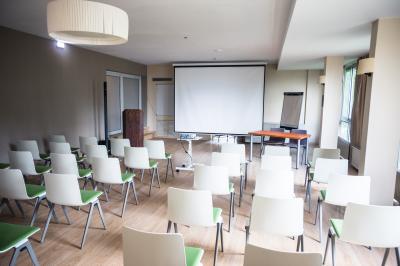 Chambre lumineuse avec un lit double, une table de chevet, une lampe et une salle de bain attenante visible en arrière-plan.