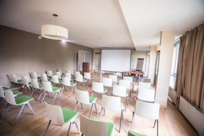 Chambre lumineuse avec un lit double, une table de chevet, une lampe et une salle de bain attenante visible en arrière-plan.