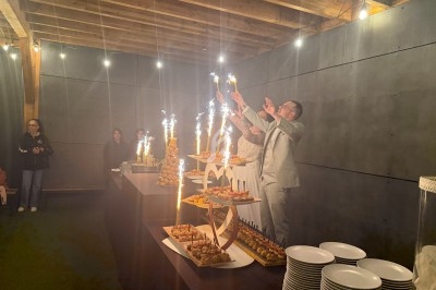 Des personnes en tenue de soirée allument des cierges magiques sur des présentoirs de buffet dans une salle éclairée.