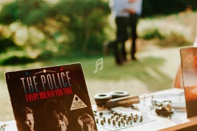 Vinyle de ’The Police’ posé sur une table de DJ en extérieur, avec un couple flou en arrière-plan.
