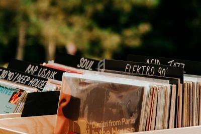 Des vinyles rangés dans des caisses en bois, avec des étiquettes indiquant différents genres musicaux.