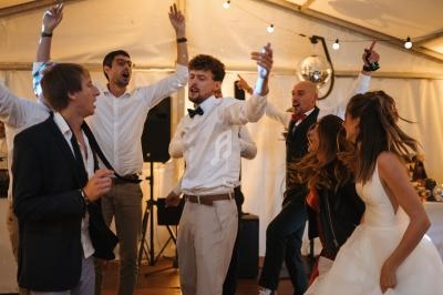 Des invités dansent et célèbrent sous une tente éclairée, lors d'une réception festive.