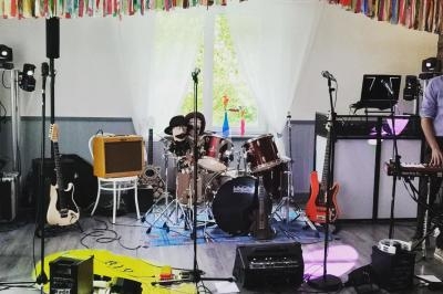 Salle décorée avec des guirlandes colorées, équipée d'instruments de musique et de matériel de sonorisation.