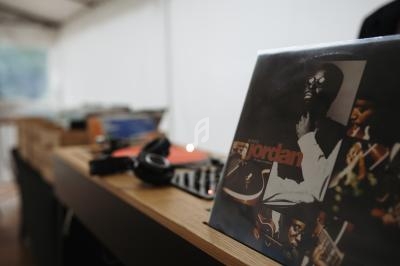 Pochette d'album vinyle sur une table en bois avec casque audio et platine en arrière-plan flou.