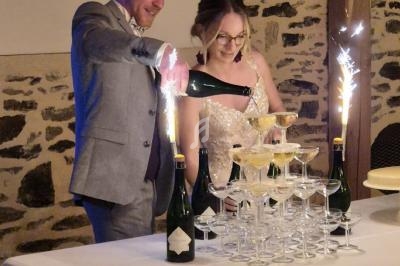 Un couple habillé élégamment verse du champagne dans une pyramide de verres avec des cierges allumés.