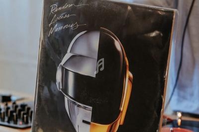 Pochette d'album avec un casque futuriste posée sur une table de mixage près d'un disque vinyle.