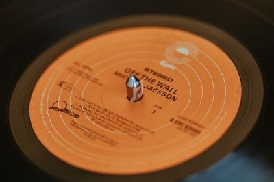 Disque vinyle noir en gros plan, avec une étiquette orange indiquant ’Off the Wall’ de Michael Jackson.