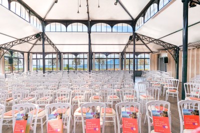 Salle de réception lumineuse avec des invités assis à des tables rondes sous un éclairage violet.