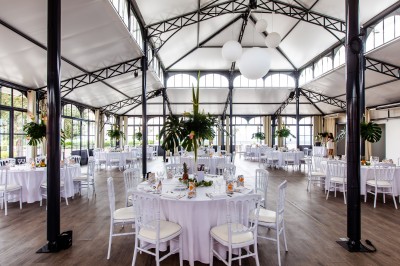 Salle de réception lumineuse avec des invités assis à des tables rondes sous un éclairage violet.