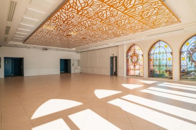Salle de réception lumineuse avec des invités assis à des tables rondes sous un éclairage violet.