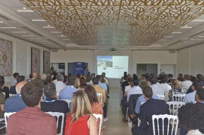 Salle de réception lumineuse avec des invités assis à des tables rondes sous un éclairage violet.