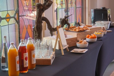 Salle de réception lumineuse avec des invités assis à des tables rondes sous un éclairage violet.