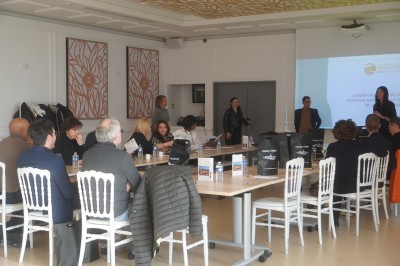 Salle de réception lumineuse avec des invités assis à des tables rondes sous un éclairage violet.