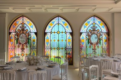 Salle de réception lumineuse avec des invités assis à des tables rondes sous un éclairage violet.