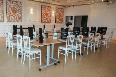Salle de réception lumineuse avec des invités assis à des tables rondes sous un éclairage violet.