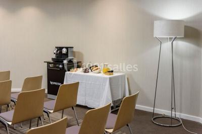Salle lumineuse avec table en bois, chaises modernes, coin salon, lit double et murs aux tons neutres et bleu.