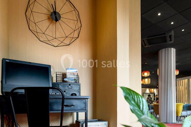 Bureau avec ordinateur noir, chaise assortie et décoration murale géométrique dans un espace intérieur lumineux.