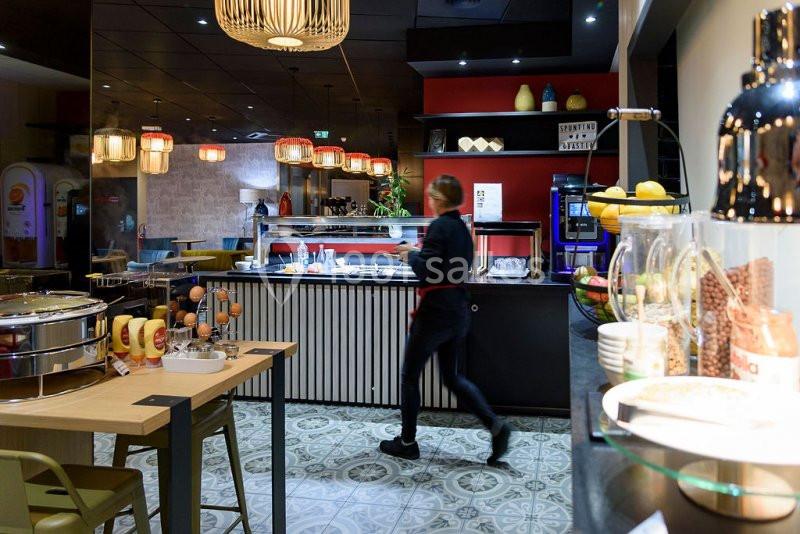 Une personne marche dans un buffet de restaurant moderne avec des plats, des fruits et des décorations lumineuses.