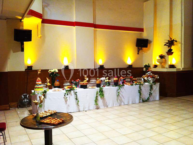 Table décorée avec nappes blanches, garnie de desserts variés et entourée d'une ambiance lumineuse chaleureuse.