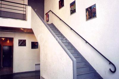 Salle avec mezzanine, tables et chaises jaunes, projection d'un match de rugby sur un mur, éclairage chaleureux.