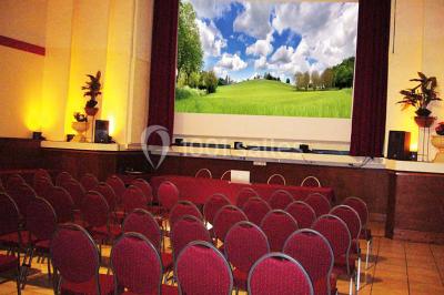 Salle avec mezzanine, tables et chaises jaunes, projection d'un match de rugby sur un mur, éclairage chaleureux.
