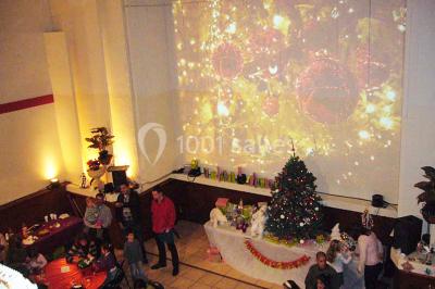 Salle avec mezzanine, tables et chaises jaunes, projection d'un match de rugby sur un mur, éclairage chaleureux.