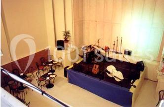 Salle avec une petite scène équipée d'instruments de musique, entourée de tables et chaises vides.